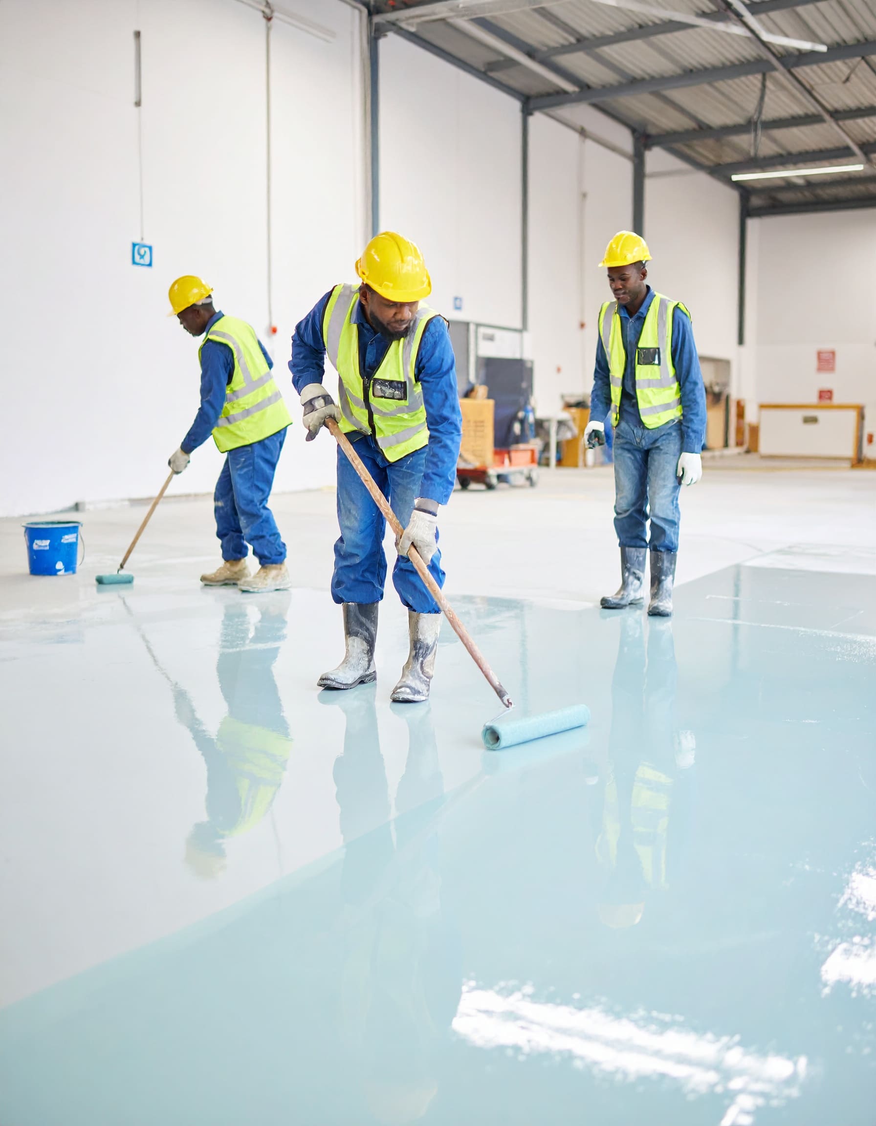Firefly_A realistic image showing African technicians applying epoxy flooring inside a commer 94726